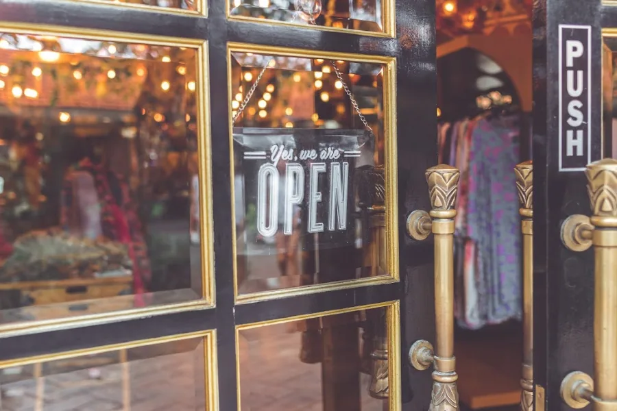 A clothing store’s door with a “Yes, we are open” sign.