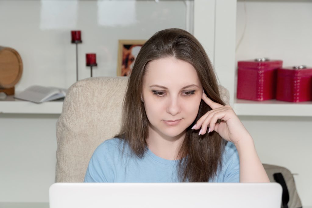 Woman with writer's block staring at her laptop because she hates writing blogs.