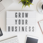 "Grow Your Business" sign laying on a work desk.
