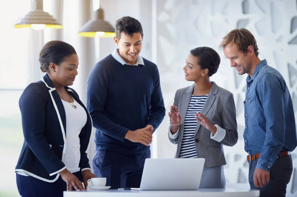 Group standing around a laptop discussing where their website traffic is coming from.
