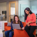Two women looking at a laptop to evaluate their digital marketing success.