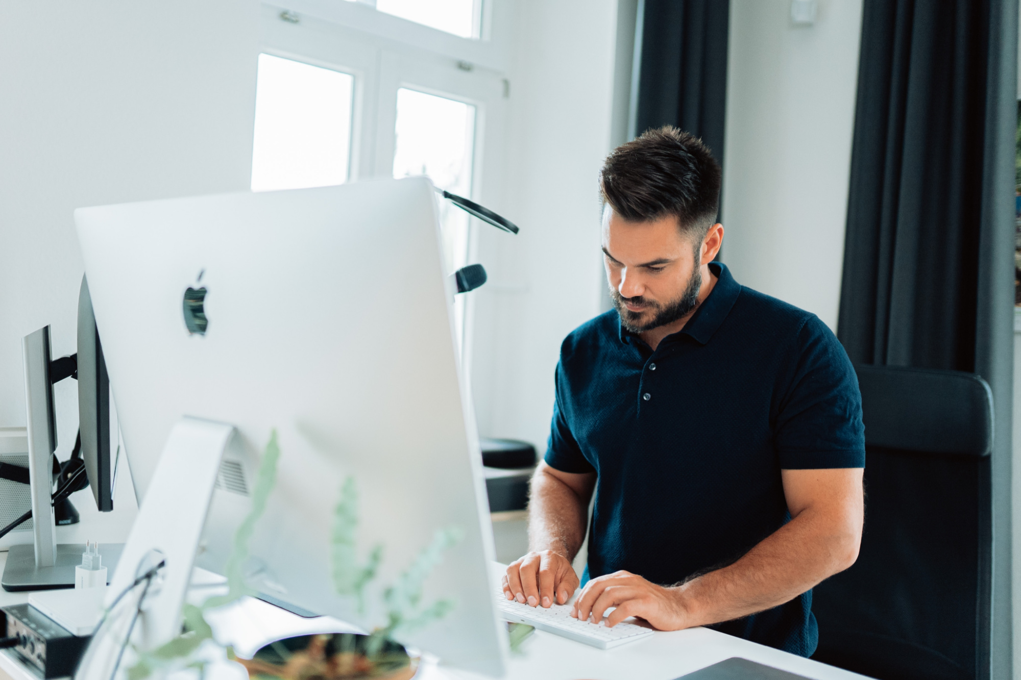 Man standing at his computer thinking about how to implement SEO tips and tricks.