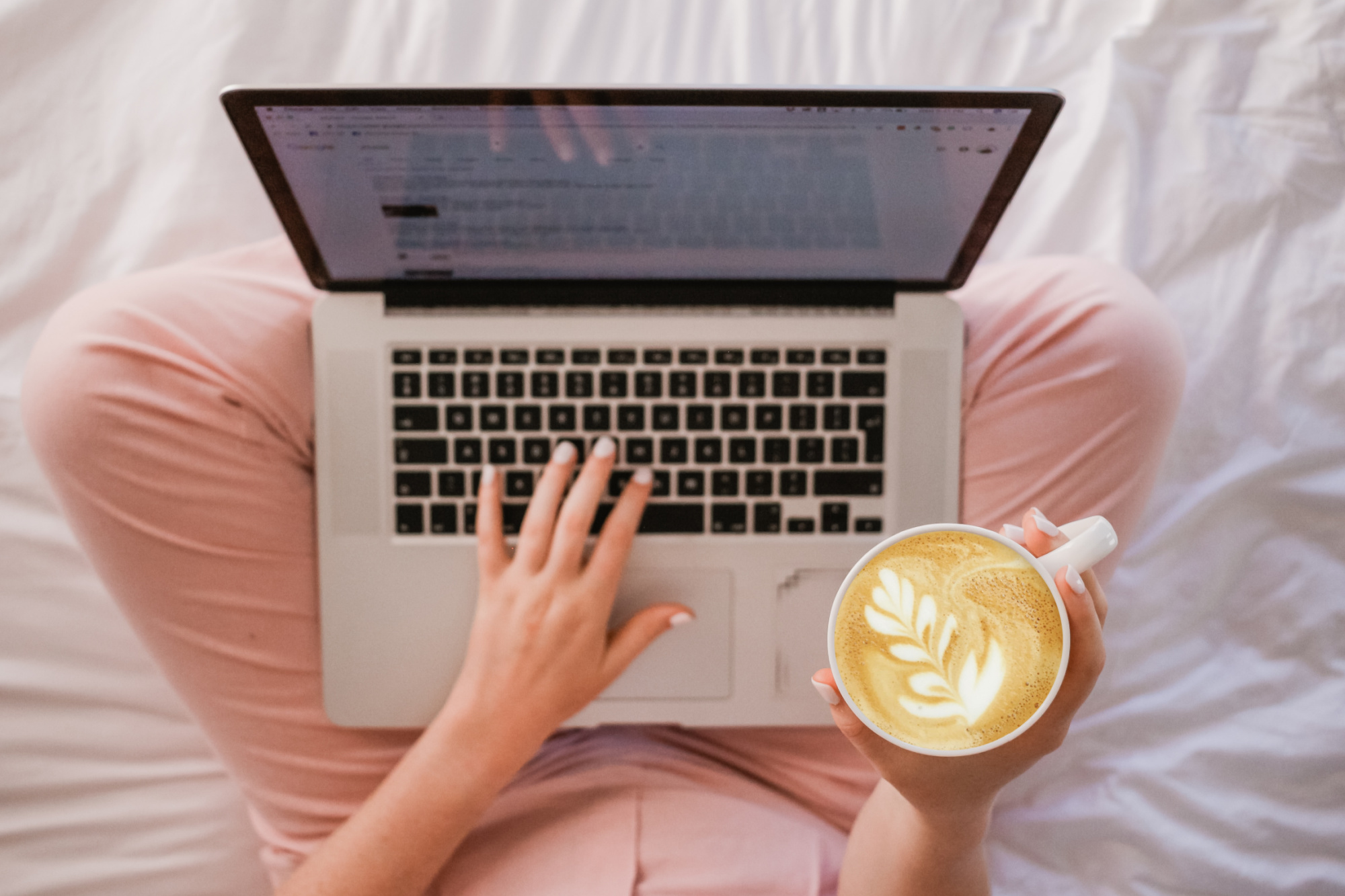Woman using an SEO checklist for blog posts while she's blogging and holding a cup of coffee.
