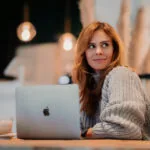 Woman sitting at her laptop wondering how to improve her digital content marketing strategy.