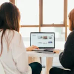 Two women discussing the balance of direct vs organic traffic to grow their business.