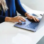 Woman starting to work on her laptop wishing she know how to write blog posts faster.