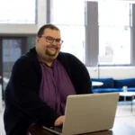 Smiling man creating his SEO content strategy on his laptop.