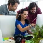 3 co-workers discussing the future of SEO as they collaborate on new content for their business.