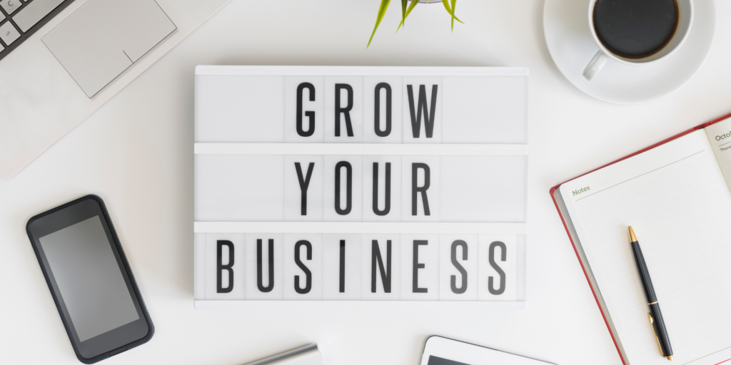 "Grow Your Business" sign laying on a work desk.