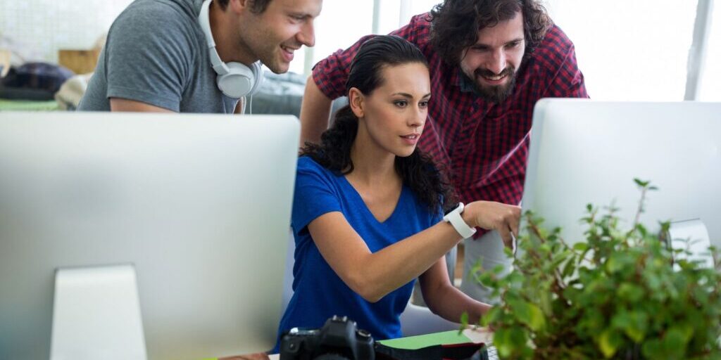 The-Future-of-SEO-Isn’t-Dead-But-the-Old-Playbook-Is-1 3 co-workers discussing the future of SEO as they collaborate on new content for their business.