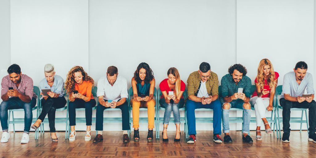 A group of people looking at their phones; apparently on social media.