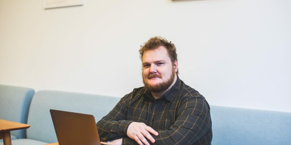 Man sitting at table with his laptop in front of him and thinking about writing blogs for SEO.