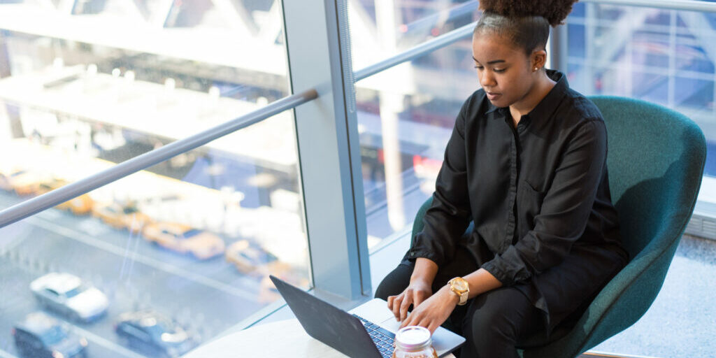 Woman sitting in an office building using her laptop to create an online marketing campaign.