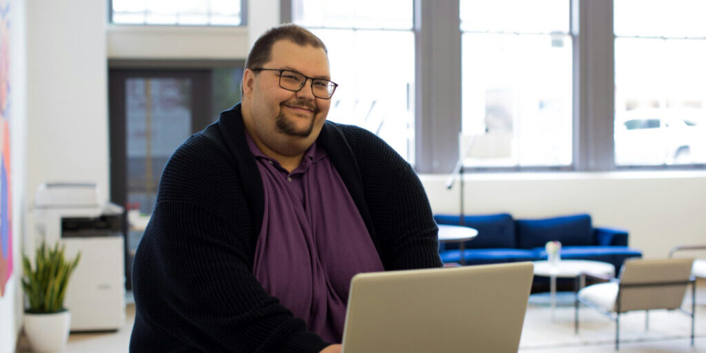 Smiling man creating his SEO content strategy on his laptop.