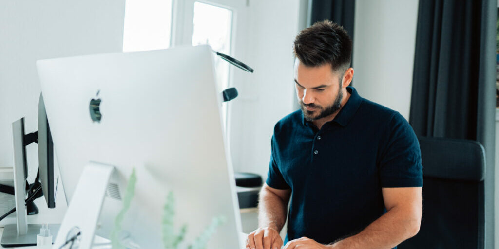 Man standing at his computer thinking about how to implement SEO tips and tricks.