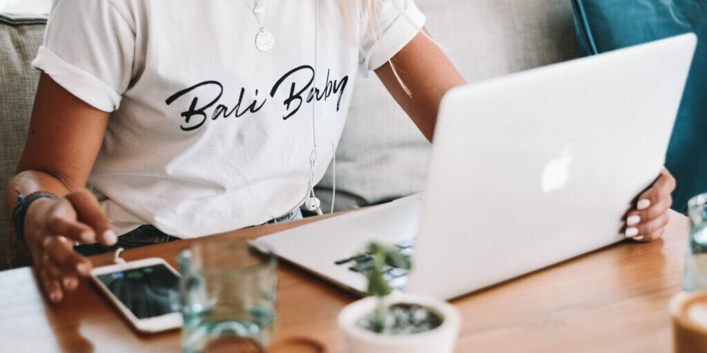 Health & wellness professional at her laptop trying to decide between SEO and local SEO to market her business.