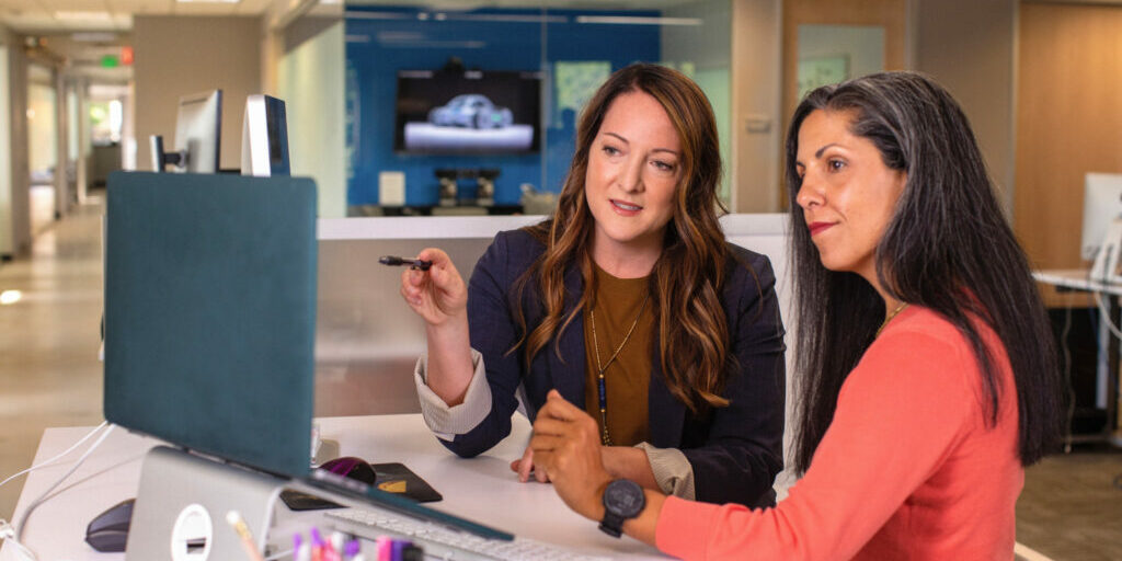 Two women looking at a computer discussing website traffic.