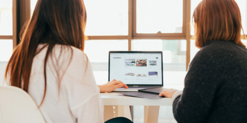 Two women reviewing the number of website visitors they've had in the last month.