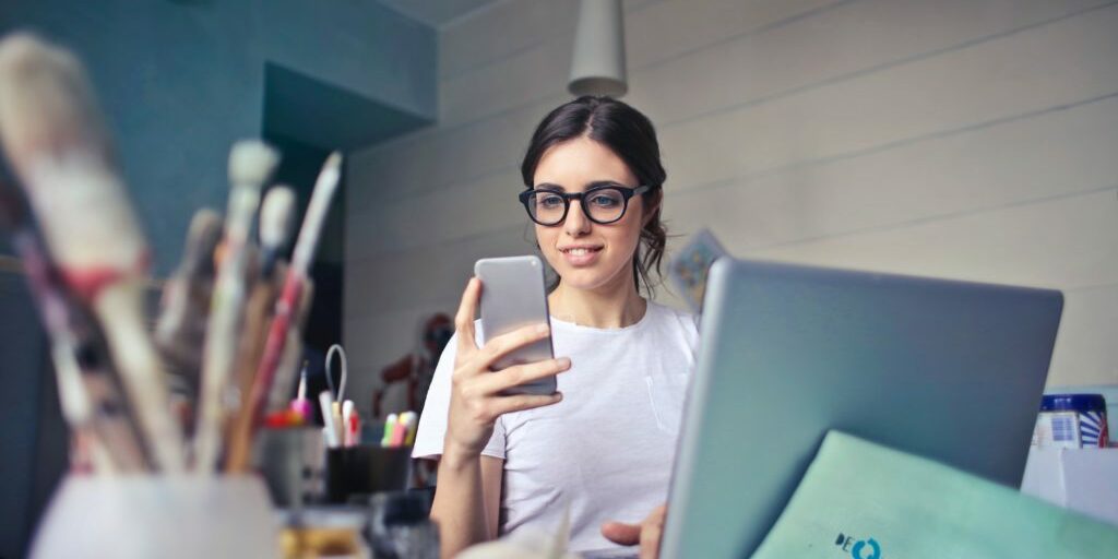 Woman taking a break from blogging to look at recent sales on her phone.